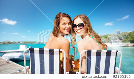 beautiful happy women sunbathing on beach chairs 92165395