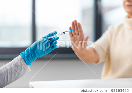 nurse with syringe and woman refusing from vaccine 92165433