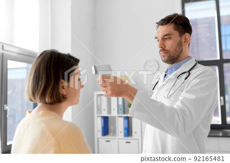 doctor with thermometer and woman at hospital 92165481