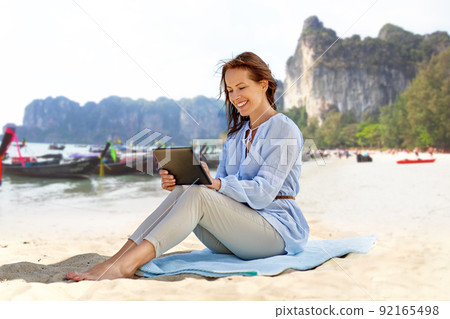 happy smiling woman with tablet pc on summer beach happy smiling woman with tablet pc on summer beach 92165498