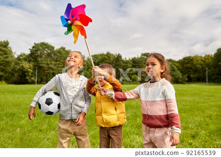 happy children playing with pinwheel at park 92165539