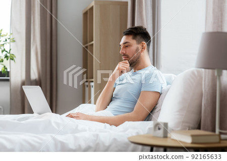 man with laptop in bed at home bedroom man with laptop in bed at home bedroom 92165633