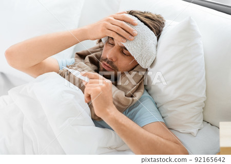 sick man measuring temperature by thermometer sick man measuring temperature by thermometer 92165642