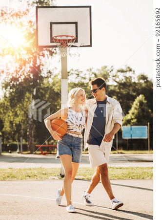 happy couple with ball on basketball playground 92165692