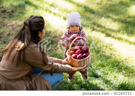 mother and baby daughter with basket of apples 92165731