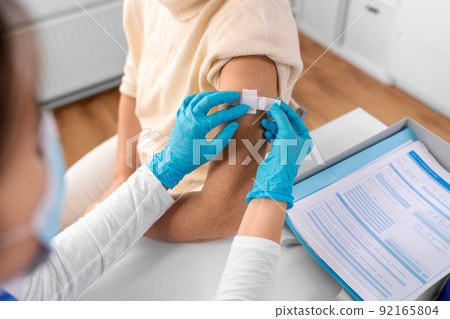 nurse applying medical patch to vaccinated woman nurse applying medical patch to vaccinated woman 92165804