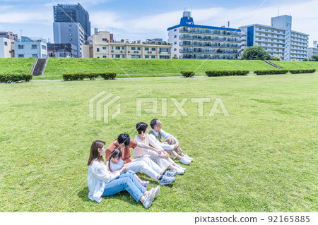 Three generations of close family members relaxing in the park Three generations of close family members relaxing in the park 92165885