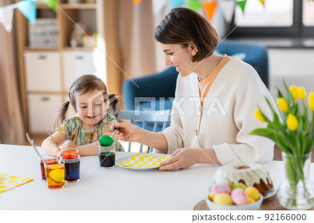 mother with child dyeing easter eggs at home 92166000