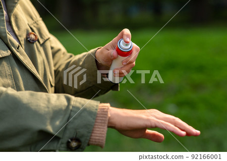 woman spraying insect repellent to hand at park woman spraying insect repellent to hand at park 92166001