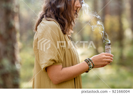 woman with sage performing magic ritual in forest woman with sage performing magic ritual in forest 92166004