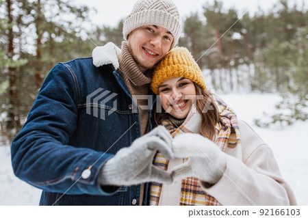 happy couple making hand heart gesture in winter 92166103
