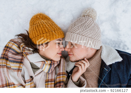 happy smiling couple lying on snow in winter happy smiling couple lying on snow in winter 92166127