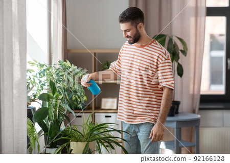 man spraying houseplant with water at home man spraying houseplant with water at home 92166128