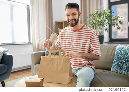 smiling man unpacking takeaway food at home 92166132