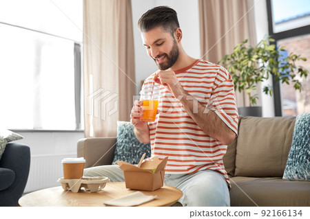 smiling man with takeaway food and drinks at home smiling man with takeaway food and drinks at home 92166134