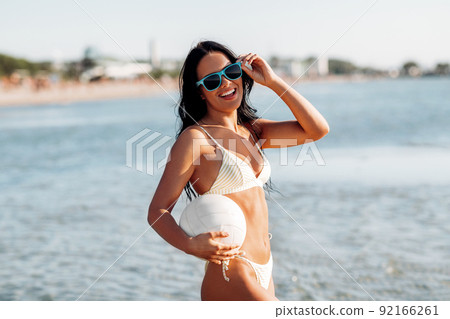 woman in bikini posing with volleyball on beach 92166261