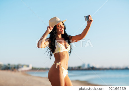 smiling woman in bikini taking selfie on beach smiling woman in bikini taking selfie on beach 92166289