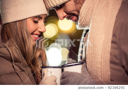 happy couple with tea cups over christmas lights happy couple with tea cups over christmas lights 92166291
