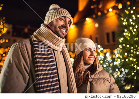 happy smiling couple over christmas lights happy smiling couple over christmas lights 92166296