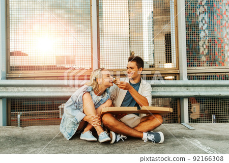 happy couple eating pizza on city roof top parking 92166308
