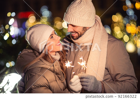 happy couple with sparklers over christmas lights 92166322