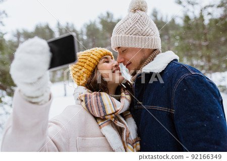 couple with smartphone taking selfie in winter 92166349