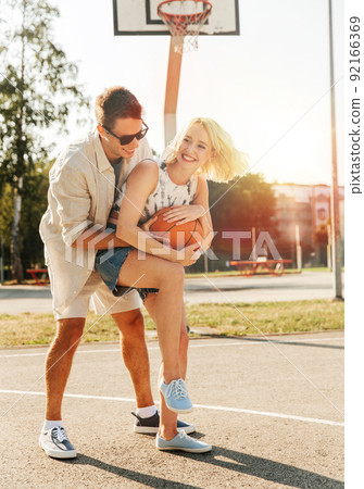 happy couple playing on basketball on playground happy couple playing on basketball on playground 92166369