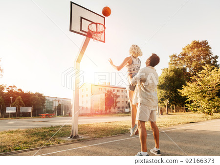 happy couple playing on basketball on playground happy couple playing on basketball on playground 92166373