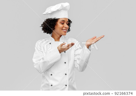 smiling female chef holding something on hand smiling female chef holding something on hand 92166374