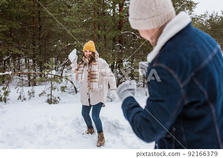 happy couple playing snowballs in winter park 92166379