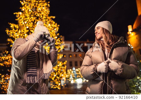 couple with camera photographing at christmas city couple with camera photographing at christmas city 92166410