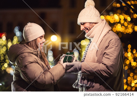 happy couple with gift over christmas lights happy couple with gift over christmas lights 92166414