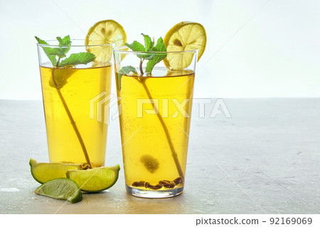 Two glass cups of homemade fermented kombucha tea are decorated with mint and lemon on a light gray concrete table 92169069