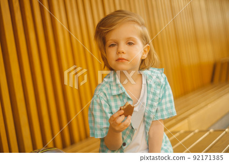 Portrait of cute boy looking at camera with a chocolate bar Portrait of cute boy looking at camera with a chocolate bar 92171385