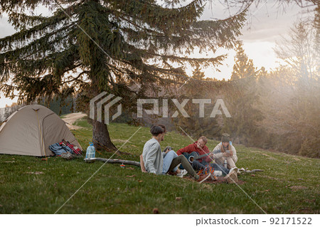 Caucasian team of friends hikers resting with guitar playing at tent in mountains. . Caucasian team of friends hikers resting with guitar playing at tent in mountains. . 92171522