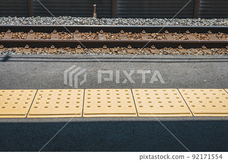 Yellow line / Braille block on the platform of the station Yellow line / Braille block on the platform of the station 92171554