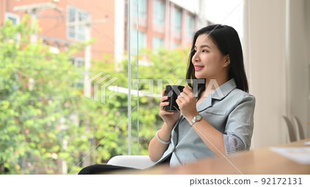 Thoughtful young businesswoman drinking coffee, dreaming about good future Thoughtful young businesswoman drinking coffee, dreaming about good future 92172131