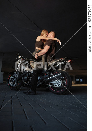 Young couple kissing sitting on a motorcycle in underground parking garage 92173085