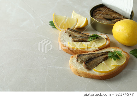 Sandwiches with sprats and ingredients on light background 92174577