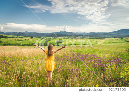 Woman in yellow dress staying at the green meadow in the mountain 92175503