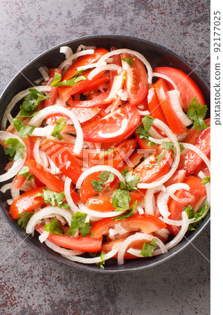 Ensalada chilena is a Chilean salad consisting of tomatoes, onions, olive oil, and coriander closeup in the plate. Vertical top view 92177025