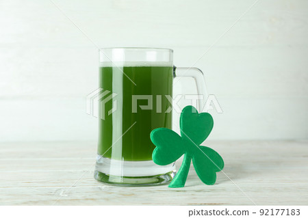 Glass of ale and clover leaf on white wooden table 92177183