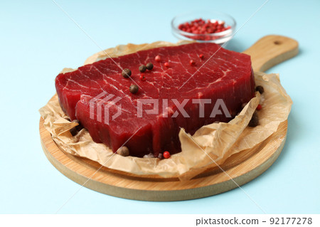 Concept of tasty food with raw beef steak on blue background Concept of tasty food with raw beef steak on blue background 92177278