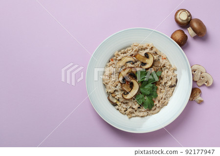 Plate of risotto with mushrooms and ingredients on violet background 92177947