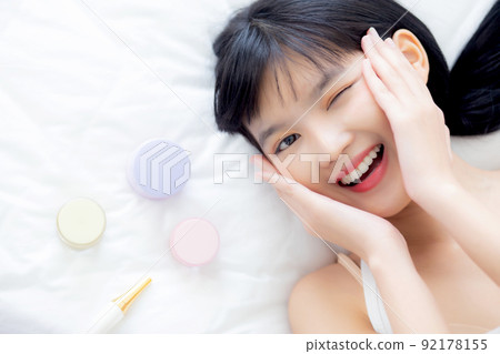 Beautiful of young asian woman smiling and lying on bed with cosmetic at bedroom. 92178155