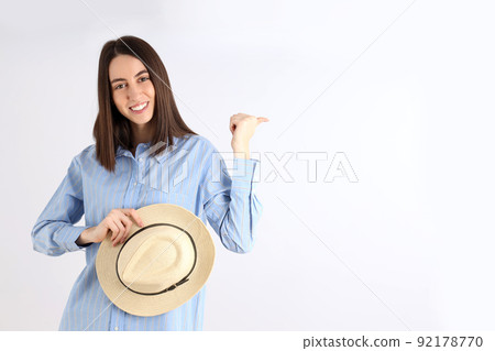 Young attractive woman in shirt holds hat on white background 92178770