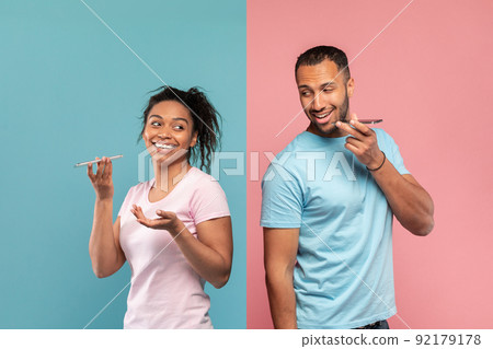 Technology and communication concept. Black woman and man recording audio messages on their cellphones Technology and communication concept. Black woman and man recording audio messages on their cellphones 92179178