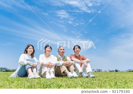 A close family relaxing in the park, sitting in a gym A close family relaxing in the park, sitting in a gym 92179180