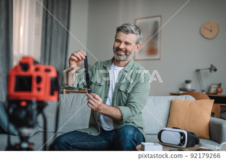 Smiling senior european male blogger records video review on technology and shows smart watch with empty screen 92179266