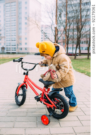 A small child learns to ride a bike for the first time in the city in spring A small child learns to ride a bike for the first time in the city in spring 92179361